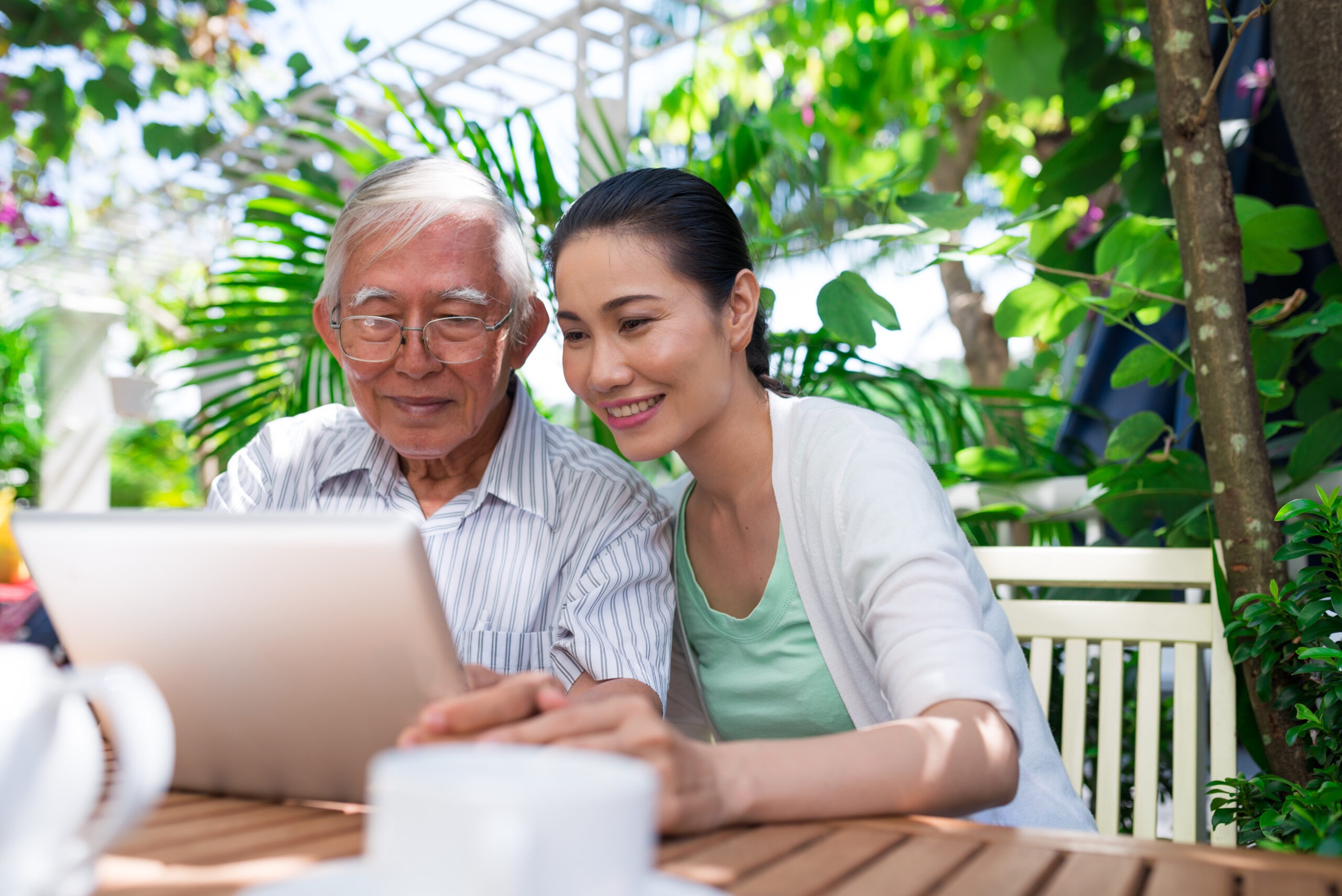 Adult child looking at iPad with senior father